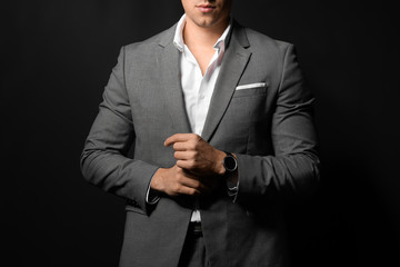 Handsome young man in elegant suit on dark background