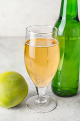 Bottle and glass of apple cider on table