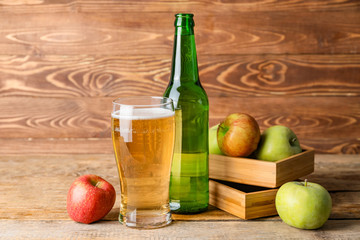 Bottle and glass of apple cider on table