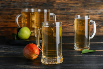 Mugs of apple cider on wooden background