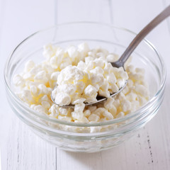 food and dairy products concept - close up of homemade cottage cheese in glass bowl on wooden table
