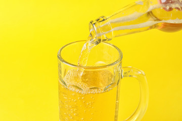 Pouring of apple cider in mug on color background