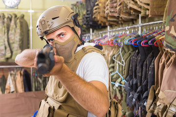 adult guy in military equipment with weapon in army shop