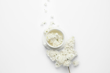 Composition with beautiful lilac flowers and cup on white background