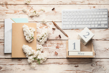 Composition with beautiful lilac flowers, PC keyboard, calendar and notebooks on wooden background