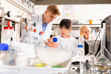 Fototapeta premium Portrait of group of European and Chinese scientists working together at biochemical laboratory