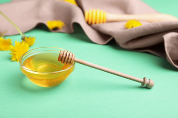 Bowl of sweet dandelion honey on color background