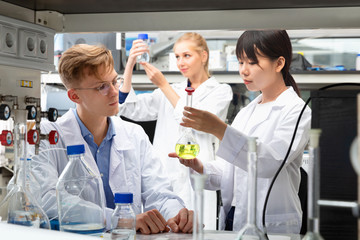 Fototapeta premium Portrait of group of European and Chinese scientists working together at biochemical laboratory