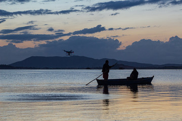 Sunset over lagoon with fisherman silhouette  in canoes , drone flying