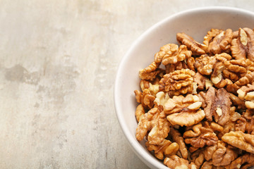 Bowl with tasty walnuts on light background