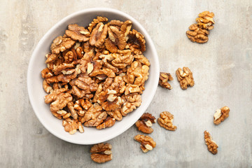 Bowl with tasty walnuts on light background