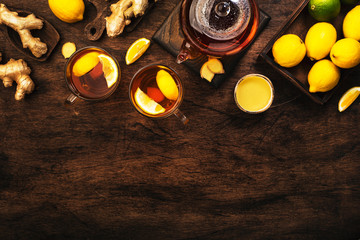 Healing black herbal tea with ginger, honey, lemon. Immune booster drink in glass cup on rustic...