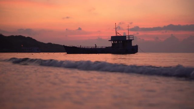 Silhouette of Commercial Fishing Boat Anchored at Shore During Colorful Sunrise in Thailand