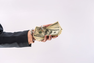 Man in handcuffs holding dollar banknotes isolated, close up