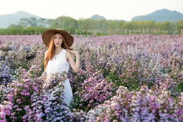 Asian woman with white dress relaxing on Margaret Aster flower field in garde