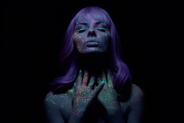Fashion model woman in neon light bright fluorescent makeup, long hair, drop on face. Beautiful model pink hair girl colorful make-up, painted skin, body art design ultraviolet