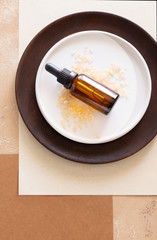 Essential aroma oil bottle and sea salt on geometric beige white background. Modern spa concept.