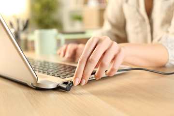 Woman hands plugging battery charger on laptop