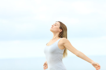 Woman breathing fresh air at the beach - obrazy, fototapety, plakaty