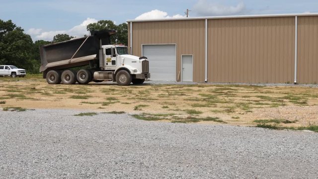 Dump truck hydraulically raising its full bed, preparing to dump