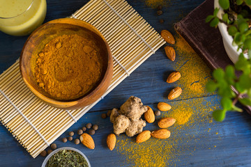 Golden milk powder and a glass with golden milk, on a blue table.