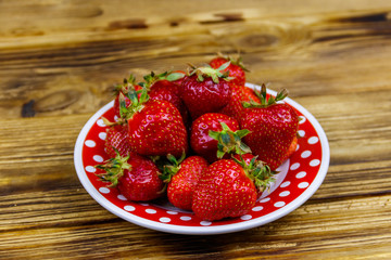 Fresh strawberry in a plate on a wooden table