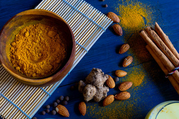 Golden milk powder and a glass with golden milk, on a blue table.