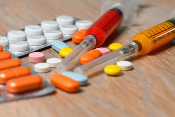 Concept of treatment options for COVID virus infection. Colorful syringes and tablets close-up.