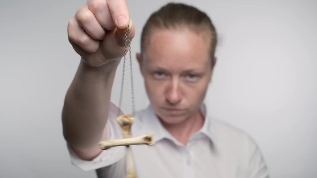 Woman hypnotist with hypnotic pendulum in hand in hypnosis session.
