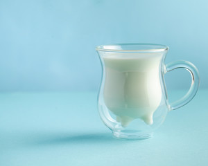 glass of milk in the shape of a cow's udder on a blue background. concept of milk, milk day, dairy products. Copy space.