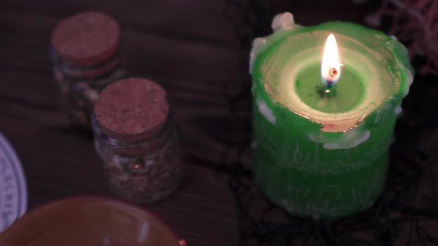 Witchcraft and wizardry. Burning green candle, Astrological pendulum for Tarot and the occult circle for fortune-telling next to magic potions and subjects. Low light, close-up