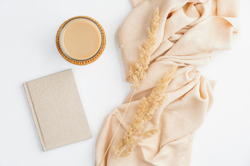 Flat lay autumn composition. Top view beige blanket, cup of coffee, paper notebook and dry flowers...