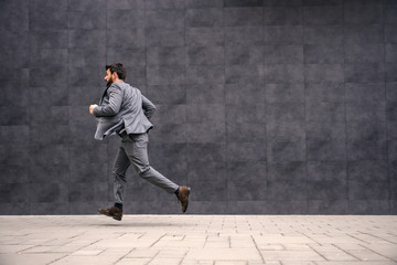 Young attractive bearded businessman running to work.