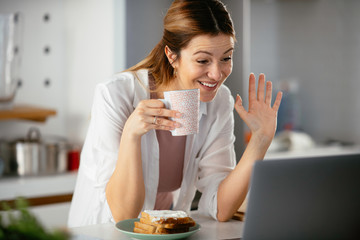 Beautiful woman eating breakfast  in the kitchen. Young woman reading the news online.	
