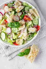 Delicious Fattoush or Arab salad with pita bread, fresh vegetables and basil on plate. Middle Eastern bread salad. Top view.