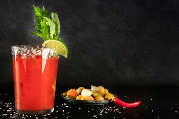 Bloody Mary cocktail with tomato juice, lime, and celery, wiuth pickles and a chili pepper, side...