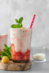 Layered strawberry and raspberry smoothie or milkshake in glasses decorated with mint, raspberry and coconut flakes. Healthy food for breakfast or snack.