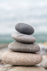 Fototapeta na wymiar Pyramid of sea stones on the seashore at the pebble beach. Concept of harmony and balance.
