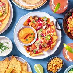 Mexican food, a flat lay. Nachos, tortillas, Paloma cocktails and other dishes, overhead square shot