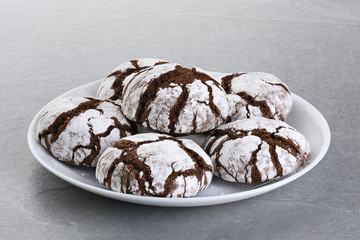 Chocolate chip cookie with cracks on a gray background.
