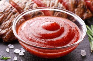 Beef steak, ketchup and rosemary on a slate board background. Roast beef medium rare.