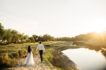 Wedding photo, wife and husband walking outdoor at sunset 