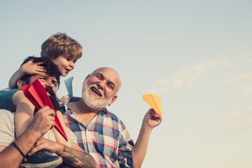 Men generation. Happy child playing with toy paper airplane against summer sky background. Cute son...