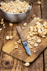 Freshly chopped Hazelnuts on an old wooden table (close up; selective focus)