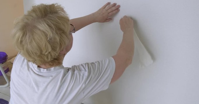 During quarantine woman decided to make repairs in her apartment, glues wallpaper herself, wipes glue from glue with clean rag, joins pattern, handyman, can&rsquo;t leave house, found something to do