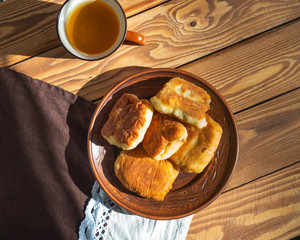 Homemade pies on a brown plate standing on a wooden table top view