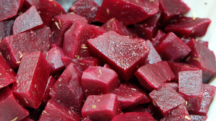 Closeup of beetroot salad, cut into cubes, with mixed herbs sprinkled on top.