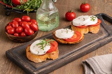 mozzarella with tomato slice on the toast on wooden board