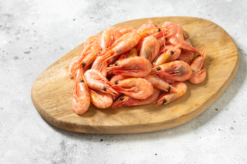 Prawns on a wooden Board on the light gray kitchen table. Lots of prawns on the serving Board