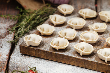 Fototapeta na wymiar Semi-finished pelmeni dumplings on wooden board